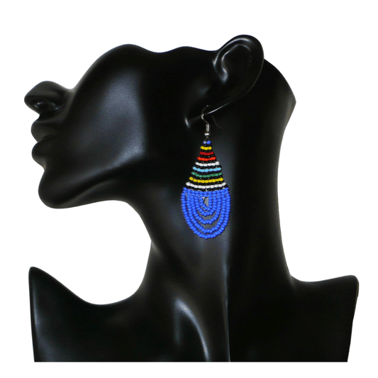 Boucles d'oreilles sud-africaines zouloues en forme de gouttes composées d'un tissage de perles de rocaille bleues et multicolores. Elles mesurent 7 cm de long et 2,5 cm de large et se portent sur des oreilles percées.