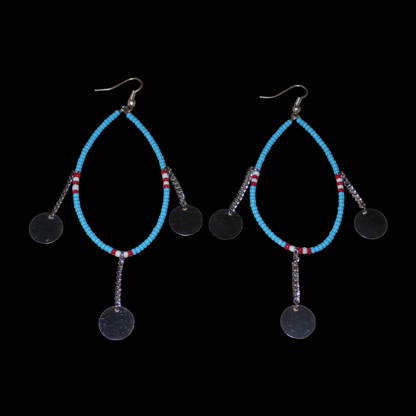 Longues boucles d'oreilles africaines Massai composées de perles bleu turquoise, blanches et rouges glissées sur un brin de fil de fer monté en forme de goutte, et de chaînettes ornées de pastilles en métal. Ces boucles d'oreilles ethniques chic mesurent 11,5 cm de long et 4 cm de large, et se portent avec des crochets en acier inoxydable sur des oreilles percées.