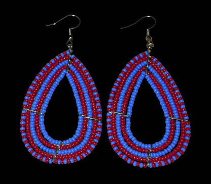 Boucles d'oreilles kenyanes bicolores rouges et bleues en forme de gouttes faites de perles de rocailles. Elles mesurent 8,5 cm de long et 4 cm de large et se portent sur des oreilles percées.