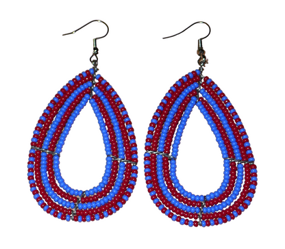 Boucles d'oreilles bicolores en perles de rocaille rouges et bleues enfilées sur cinq rangées de fils de fer montés en forme de gouttes. Elles mesurent 8,5 cm de long et 4 cm de large. Présentées sur un fond blanc.