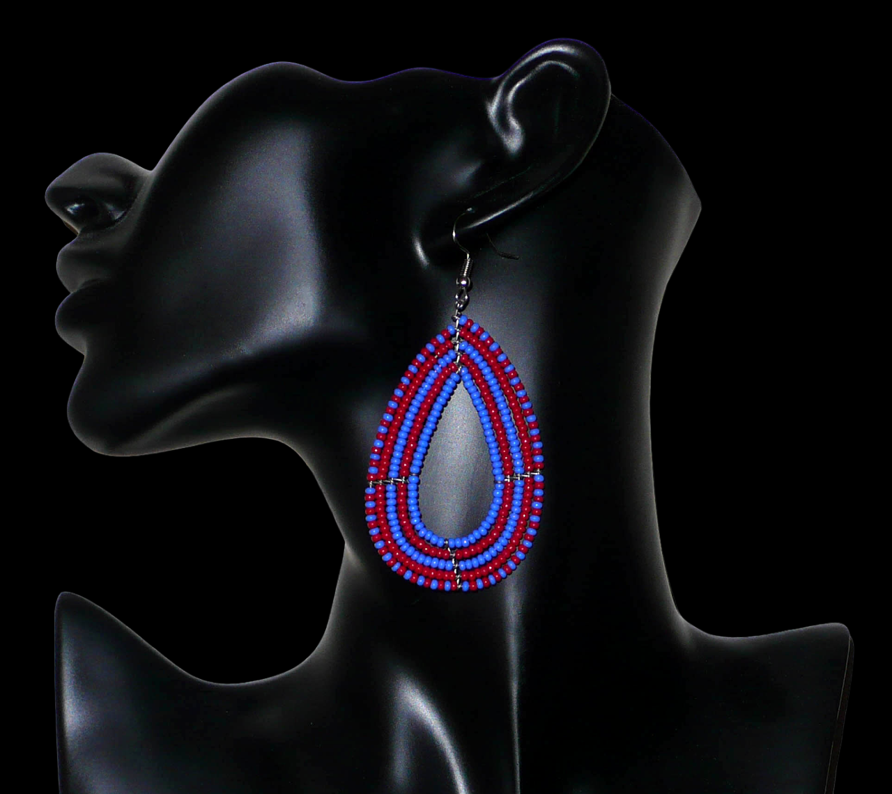 Boucles d'oreilles kenyanes bicolores rouges et bleues en forme de gouttes faites de perles de rocailles. Elles mesurent 8,5 cm de long et 4 cm de large et se portent sur des oreilles percées.