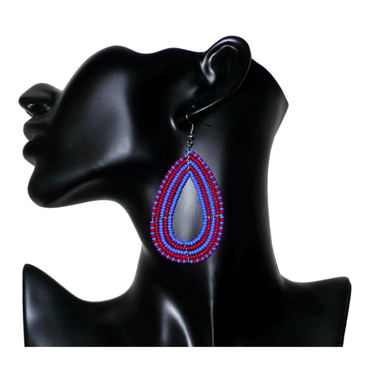 Boucles d'oreilles kenyanes bicolores rouges et bleues en forme de gouttes faites de perles de rocailles. Elles mesurent 8,5 cm de long et 4 cm de large et se portent sur des oreilles percées.