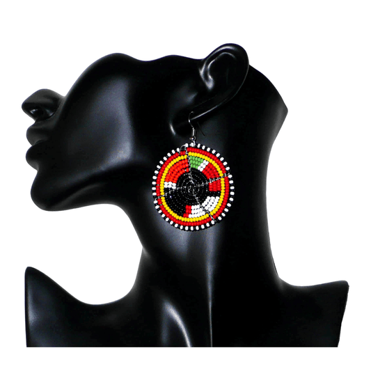 Boucles d'oreilles ethniques rondes composées de perles de rocaille noires et multicolores. De taille moyenne, ces boucles d'oreilles africaines de tradition Massai mesurent 6,5 cm de long et 4,5 cm de large ; elles se portent avec des crochets en acier inoxydable sur des oreilles percées.