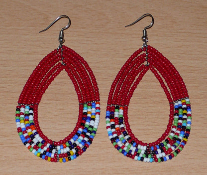 Longues boucles d'oreilles rouges et multicolores en forme de gouttes composées de perles de rocaille. Elles mesurent 9 cm de long et 4,5 cm de large et se portent avec des crochets sur des oreilles percées.