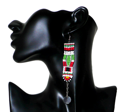 Longues boucles d'oreilles africaines de tradition Massai en perles de rocaille prolongées de chaînettes ornées de disques métalliques. Elles mesurent 11 cm de long et 2,5 cm de large, et se portent avec des crochets en acier inoxydable sur des oreilles percées.