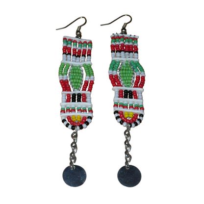 Longues boucles d'oreilles africaines de tradition Massai en perles de rocaille prolongées de chaînettes ornées de disques métalliques. Elles mesurent 11 cm de long et 2,5 cm de large, et se portent avec des crochets en acier inoxydable sur des oreilles percées.
