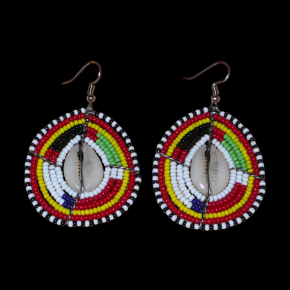 Boucles d'oreilles africaines traditionnelles en forme de boucliers Massai faites de perles et de coquillages cauris ; elles mesurent 7 cm de long et 4 cm de large et se portent sur des oreilles percées.