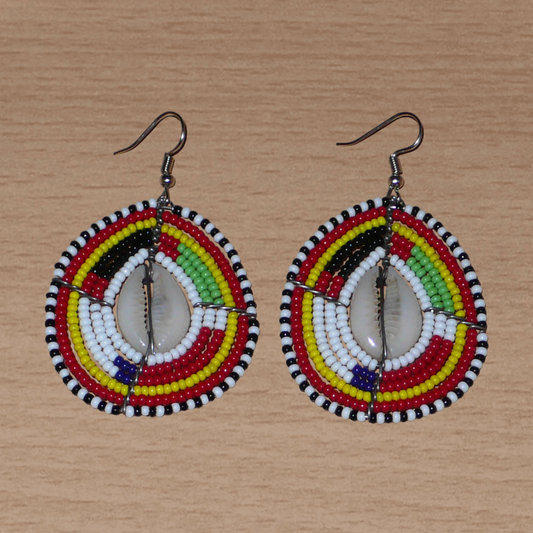 Boucles d'oreilles africaines traditionnelles en forme de boucliers Massai faites de perles et de coquillages cauris ; elles mesurent 7 cm de long et 4 cm de large et se portent sur des oreilles percées.