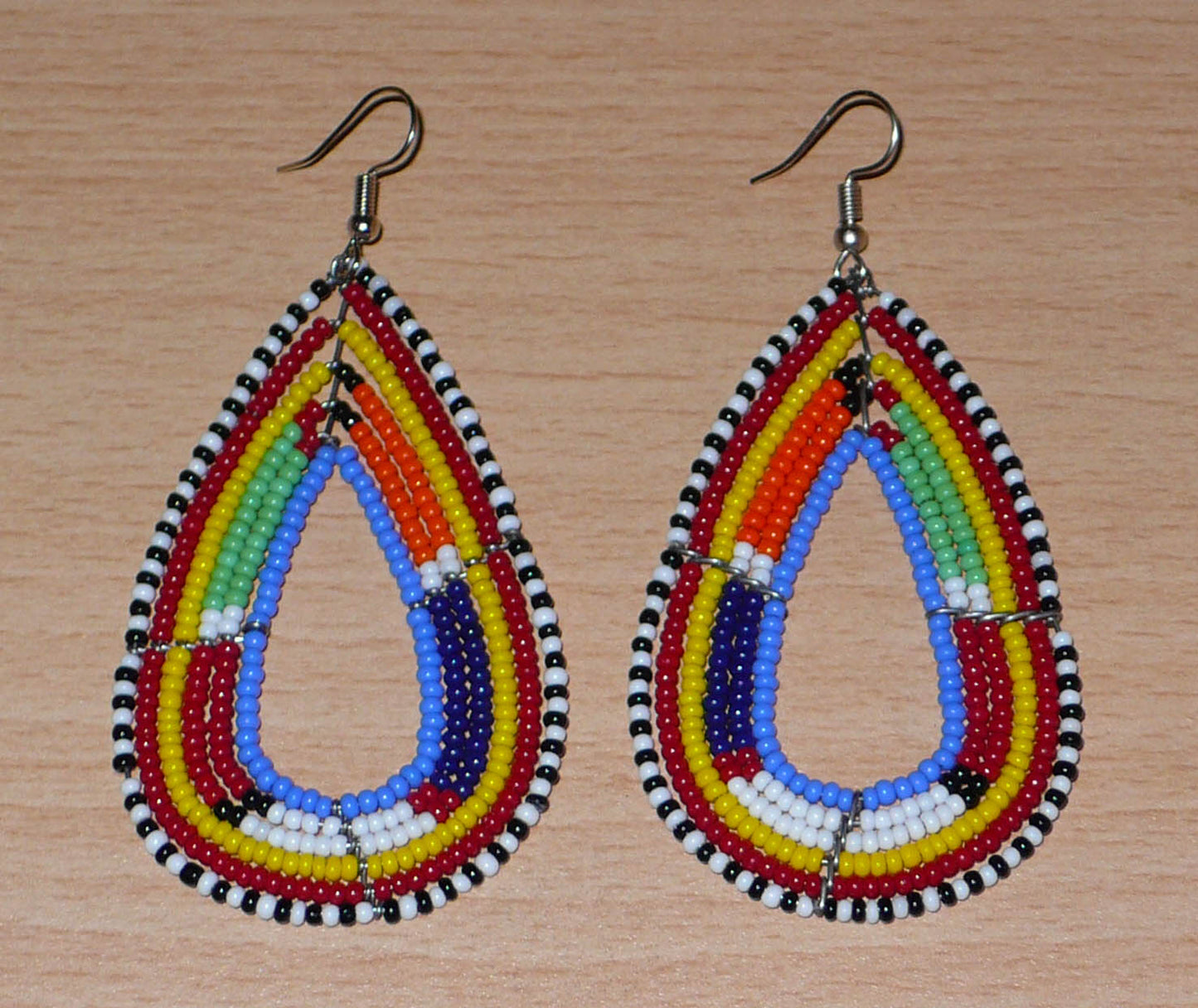 Longues boucles d'oreilles africaines en forme de gouttes faites de perles de rocaille bleues et multicolores. Elles mesurent 8,5 cm de long et 4 cm de large et se portent sur des oreilles percées.