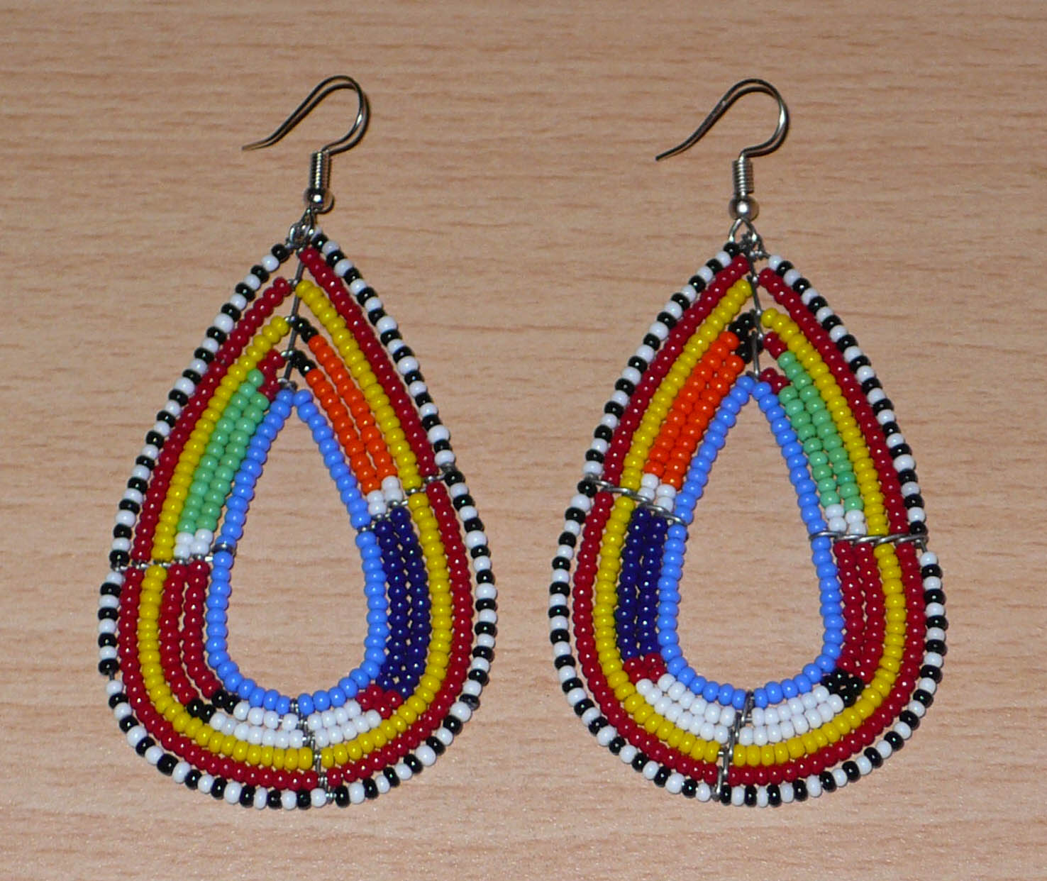 Longues boucles d'oreilles africaines en forme de gouttes faites de perles de rocaille bleues et multicolores. Elles mesurent 8,5 cm de long et 4 cm de large et se portent sur des oreilles percées.