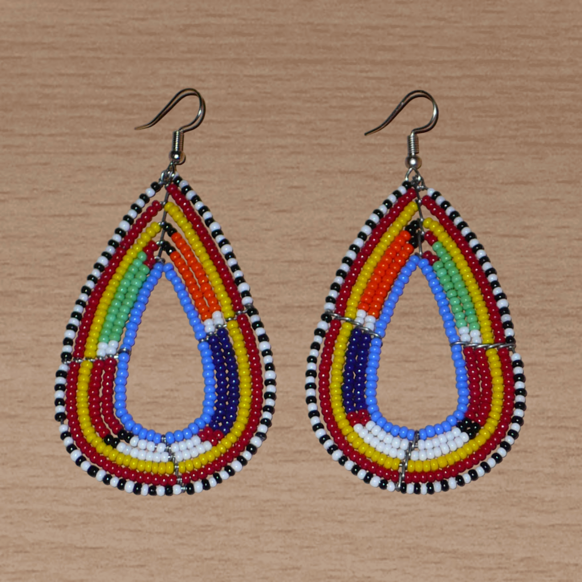 Longues boucles d'oreilles africaines en forme de gouttes faites de perles de rocaille bleues et multicolores. Elles mesurent 8,5 cm de long et 4 cm de large et se portent sur des oreilles percées.