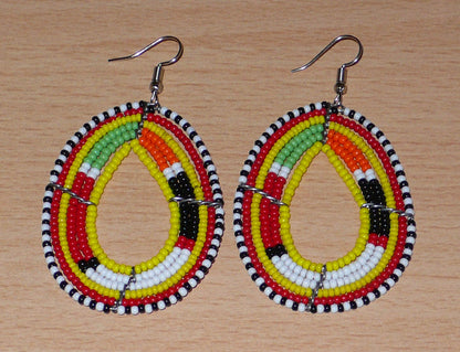 Boucles d'oreilles africaines traditionnelles aux motifs et couleurs Massai composées de perles de rocaille jaunes et multicolores fixées sur des fils de fer montés en forme de gouttes. Elles mesurent 7.5 cm de long et 4 cm de large, et se portent sur des oreilles percées.