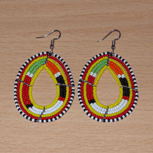 Boucles d'oreilles africaines traditionnelles aux motifs et couleurs Massai composées de perles de rocaille jaunes et multicolores fixées sur des fils de fer montés en forme de gouttes. Elles mesurent 7.5 cm de long et 4 cm de large, et se portent sur des oreilles percées.