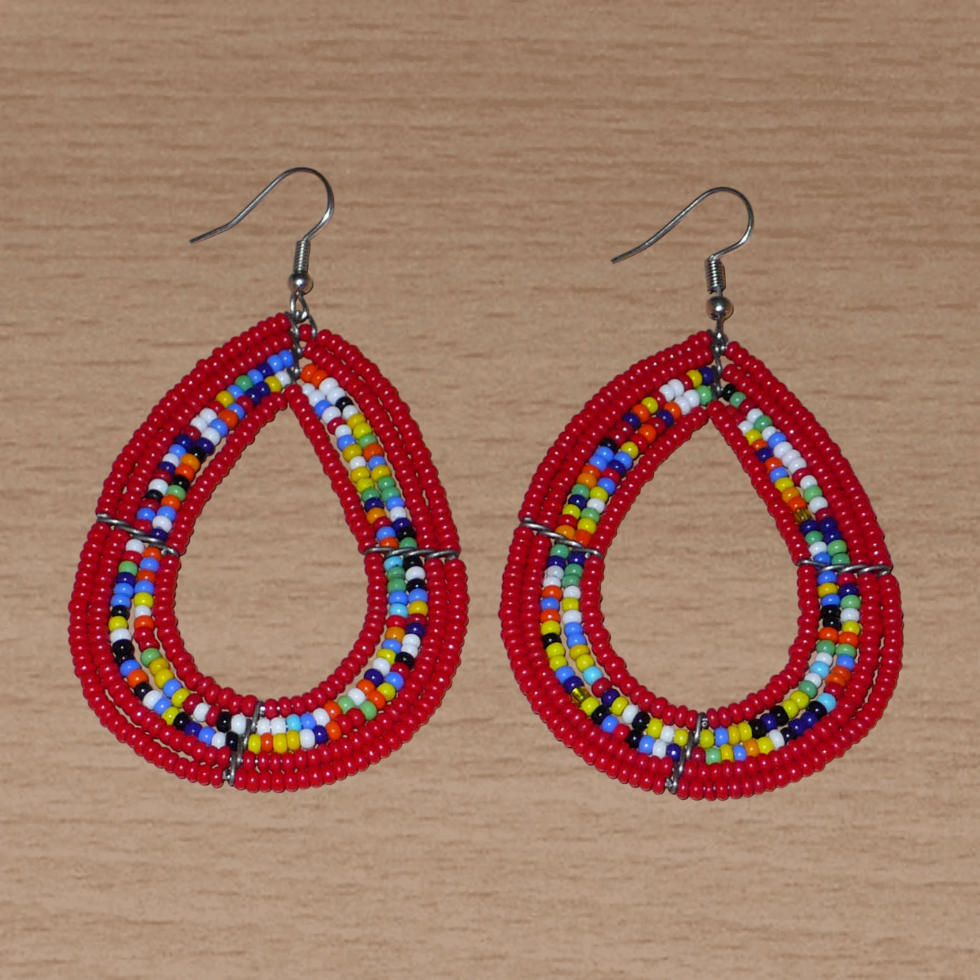 Boucles d'oreilles ethniques multi-rangs en forme de gouttes faites de perles de rocaille rouges et multicolores. Elles mesurent 8 cm de long et 4,5 cm de large, et se portent sur des oreilles percées.