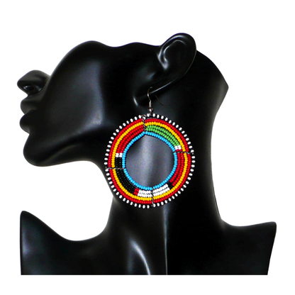 Boucles d'oreilles africaines Massai composées de perles de rocaille multicolores enfilées sur six rangées de fils de fer montés en forme de cercles. Surdimensionnées, elles mesurent 8 cm de long et 6,5 cm de large et se portent avec des crochets en acier inoxydable sur des oreilles percées.