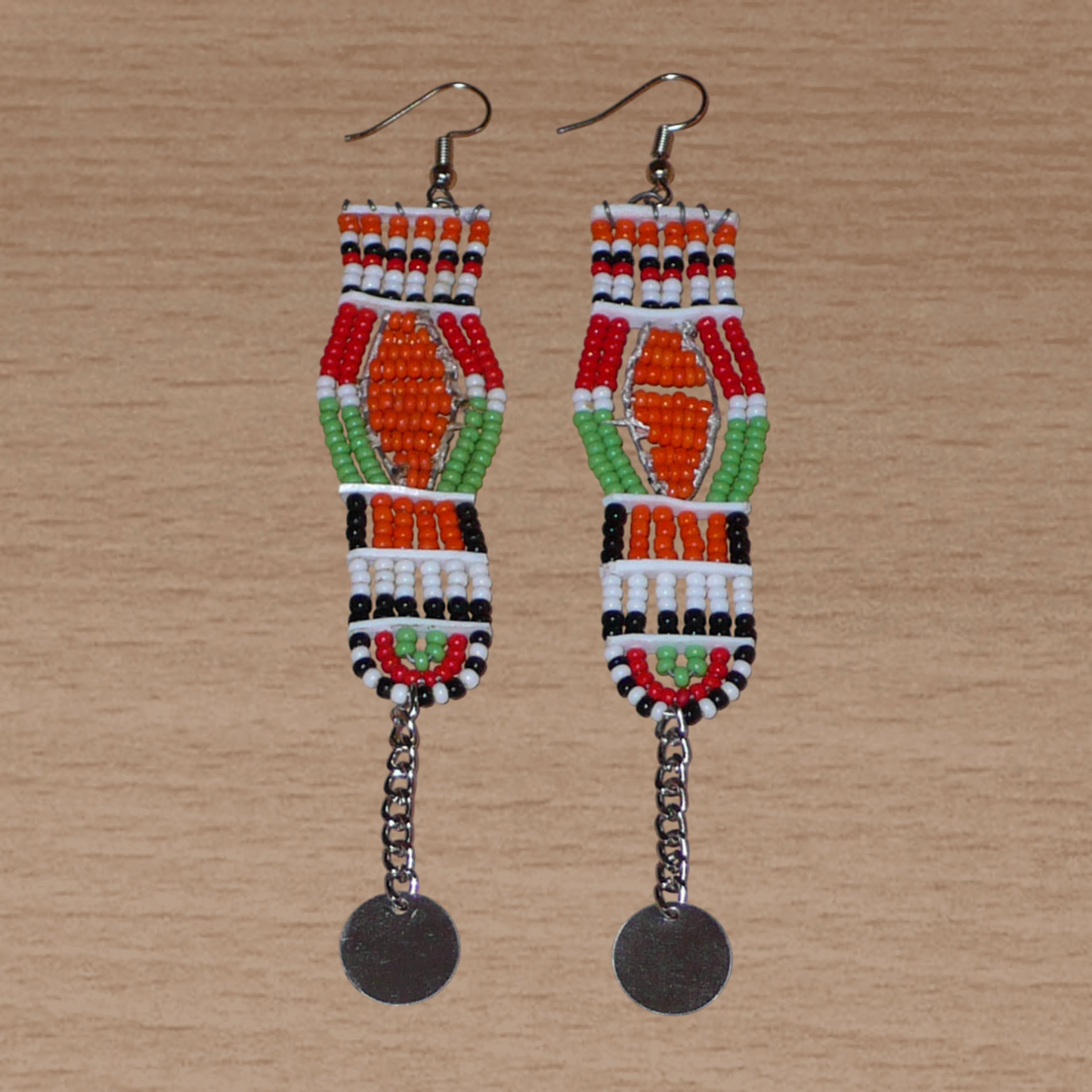 Longues boucles d'oreilles africaines Massai faites de perles de rocaille et prolongées d'une chaînette ornée d'un disque de métal. Ces boucles d'oreilles afro chic mesurent 12 cm de long et 2,5 cm de large.