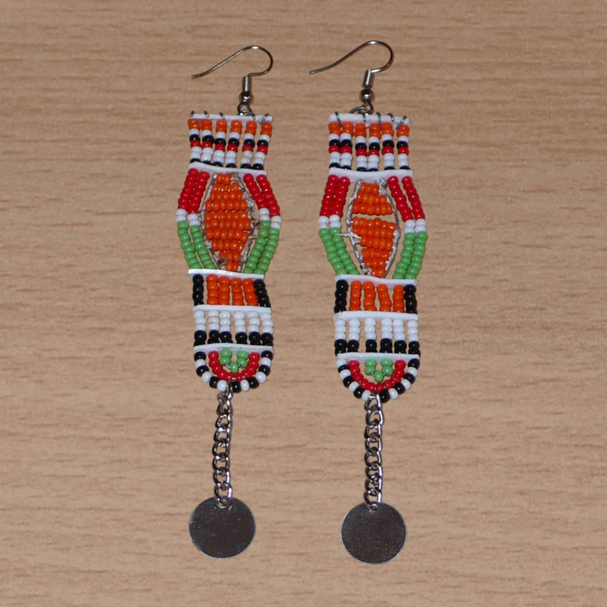Longues boucles d'oreilles africaines Massai faites de perles de rocaille et prolongées d'une chaînette ornée d'un disque de métal. Ces boucles d'oreilles afro chic mesurent 12 cm de long et 2,5 cm de large.