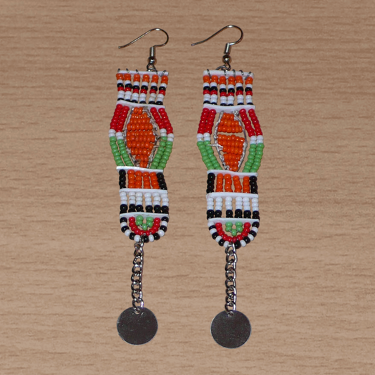 Longues boucles d'oreilles africaines Massai faites de perles de rocaille et prolongées d'une chaînette ornée d'un disque de métal. Ces boucles d'oreilles afro chic mesurent 12 cm de long et 2,5 cm de large.