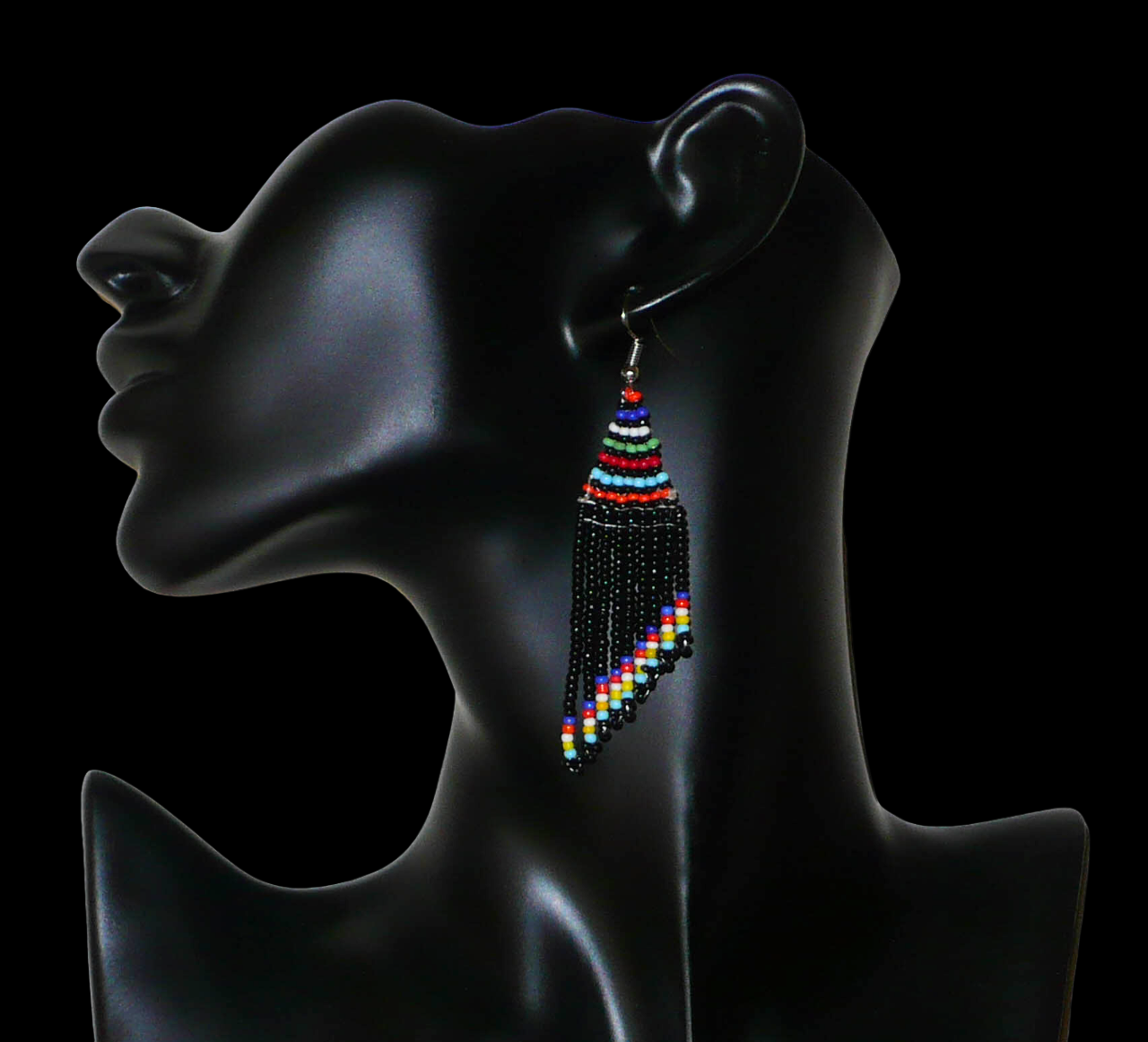 Boucles d'oreilles ethniques de tradition sud-africaine à franges perlées composées de perles de rocaille noires et multicolores. Elles mesurent 8,5 cm de long et 2 cm de large et se portent avec des crochets en acier inoxydable sur des oreilles percées.