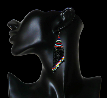Boucles d'oreilles ethniques de tradition sud-africaine à franges perlées composées de perles de rocaille noires et multicolores. Elles mesurent 8,5 cm de long et 2 cm de large et se portent avec des crochets en acier inoxydable sur des oreilles percées.