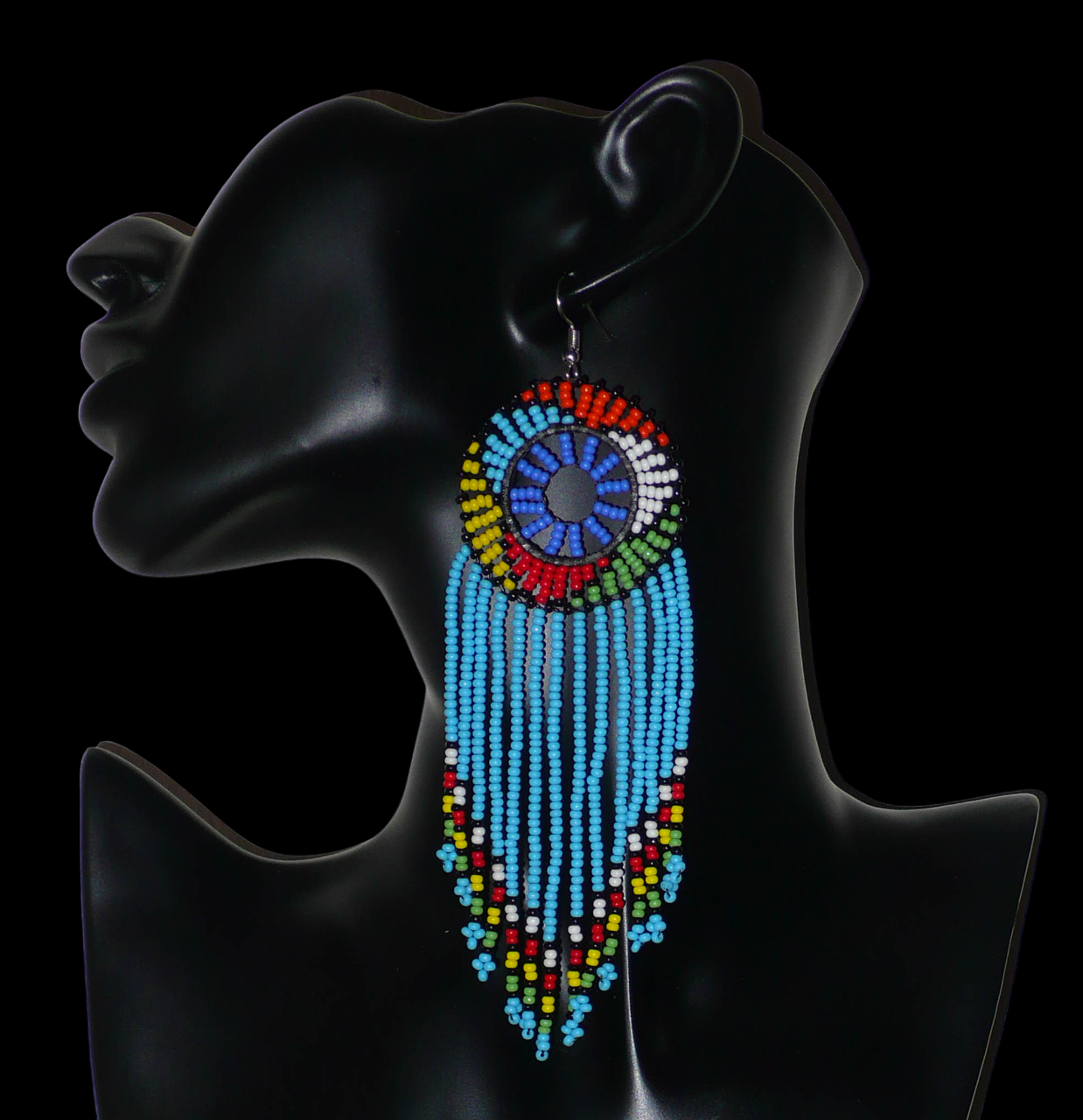 Longues boucles d'oreilles sud-africaines traditionnelles à franges et motifs zoulous composées de perles de rocaille bleu ciel et multicolores. Elles mesurent 14,5 cm de long et 4,5 cm de large, et se portent avec des crochets en acier inoxydable sur des oreilles percées.