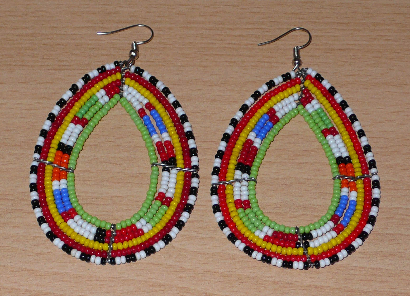 Longues boucles d'oreilles africaines Massai en perles de rocaille multicolores glissées sur six rangées de fils de fer montées en forme de gouttes. Elles mesurent 8,5 cm de long et 5 cm de large.