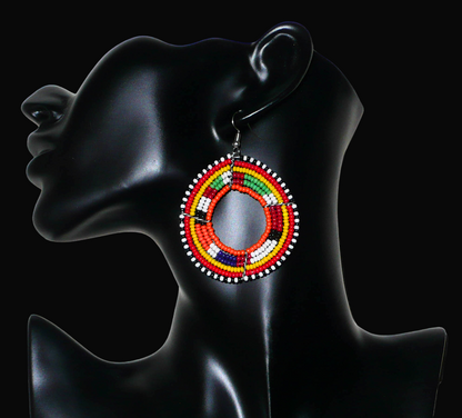 Boucles d'oreilles africaines Massai aux accents afro chic des années 70 composées de perles de rocaille orange et multicolores glissées sur des structures circulaires en fils de fer. De taille moyenne, elles mesurent 7 cm de long et 5 cm de large, et se portent sur des oreilles percées.