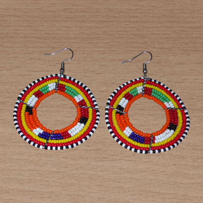 Boucles d'oreilles africaines Massai aux accents afro chic des années 70 composées de perles de rocaille orange et multicolores glissées sur des structures circulaires en fils de fer. De taille moyenne, elles mesurent 7 cm de long et 5 cm de large, et se portent sur des oreilles percées.