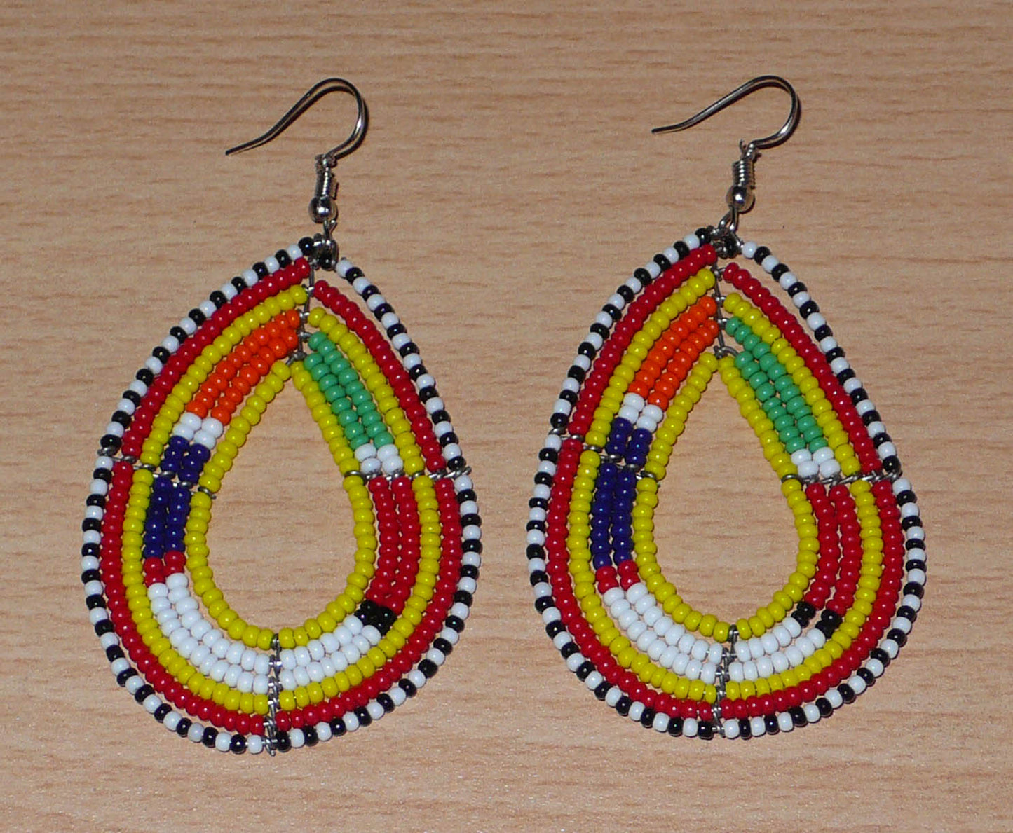 Boucles d'oreilles africaines Massai en perles de rocaille jaunes et multicolores montées en forme de gouttes. Elles mesurent 8 cm de long et 4 cm de large et se portent avec des crochets en acier inoxydable sur des oreilles percées. 