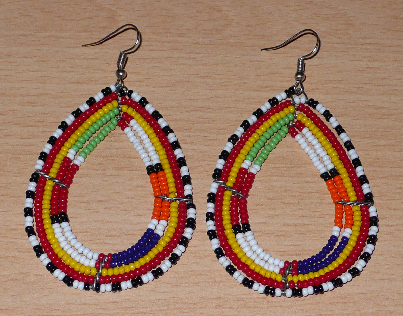 Boucles d'oreilles africaines ethniques Massai en perles de rocaille multicolores montées en forme de gouttes. Ces boucles d'oreilles colorées mesurent 8,5 cm de long et 4,5 cm de large et se portent avec des crochets en acier inoxydable sur des oreilles percées.