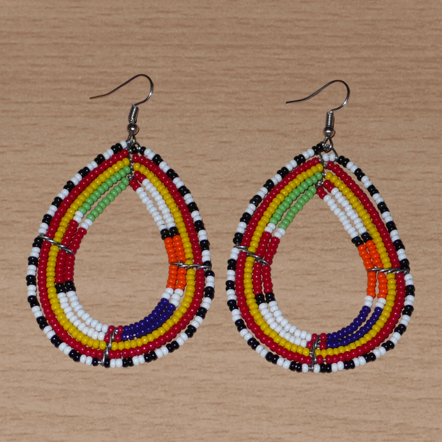 Boucles d'oreilles africaines ethniques Massai en perles de rocaille multicolores montées en forme de gouttes. Ces boucles d'oreilles colorées mesurent 8,5 cm de long et 4,5 cm de large et se portent avec des crochets en acier inoxydable sur des oreilles percées.