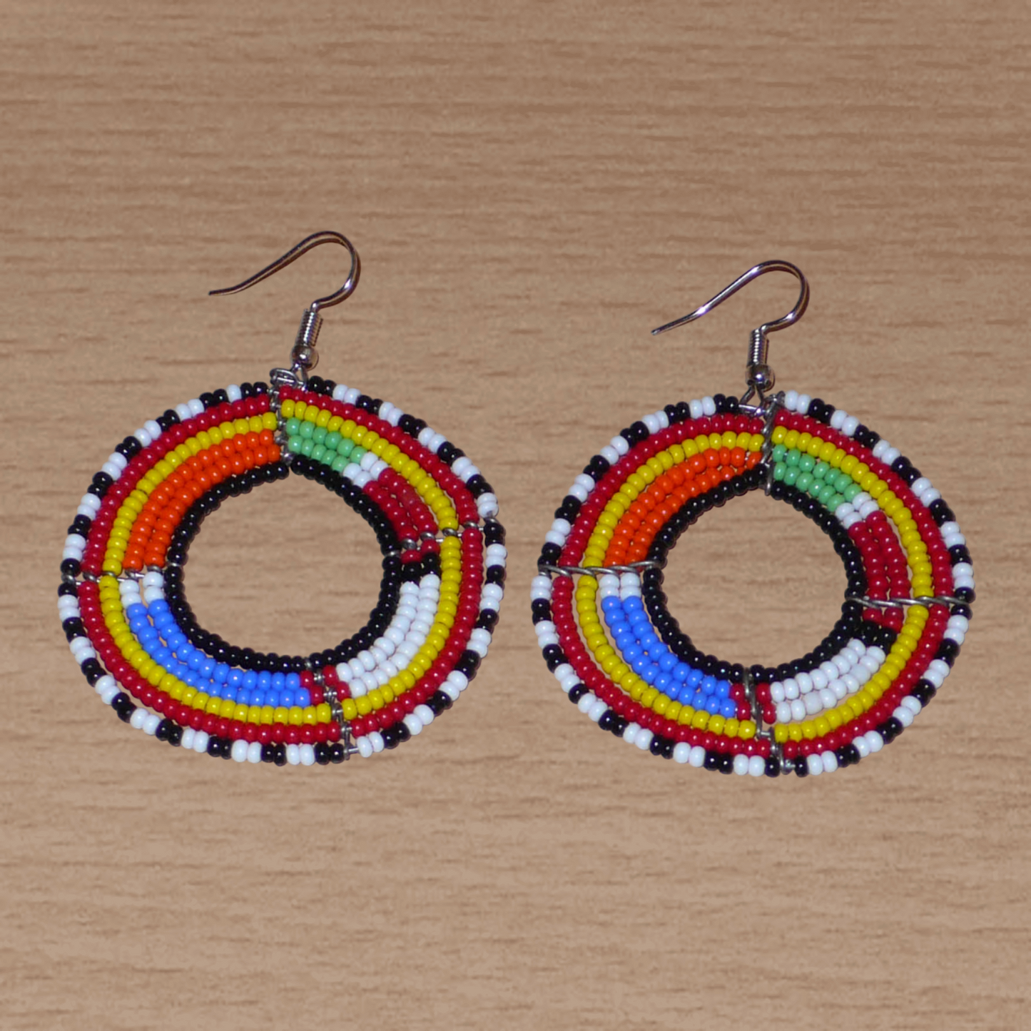 Boucles d'oreilles africaines traditionnelles Massai en perles de rocaille multicolores montées en forme de cercles. Elles mesurent  7 cm de long sur 5 cm de large.