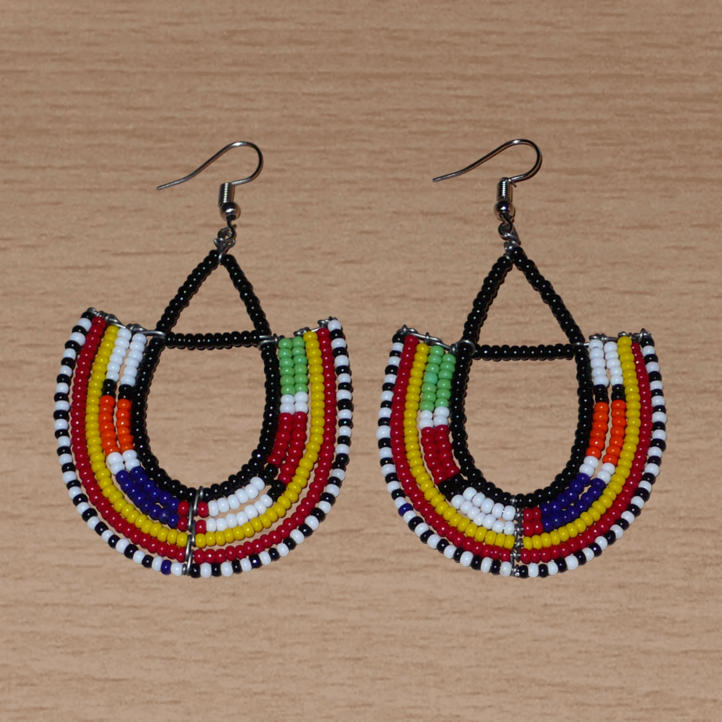 Boucles d'oreilles africaines traditionnelles fabriquées au Kenya par des femmes de la tribu Massai ; elles se composent de perles de rocaille noires et multicolores montées en forme d'ancres, et mesurent 7,5 cm de long et 4,5 cm de large. Elles se portent sur des oreilles percées avec des crochets en acier inoxydable.