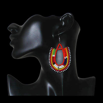 Boucles d'oreilles africaines de tradition ethnique Massai en perles de rocaille orange et multicolores montées en forme d'ancres. Elles mesurent 8 cm de long et se portent sur des oreilles percées.