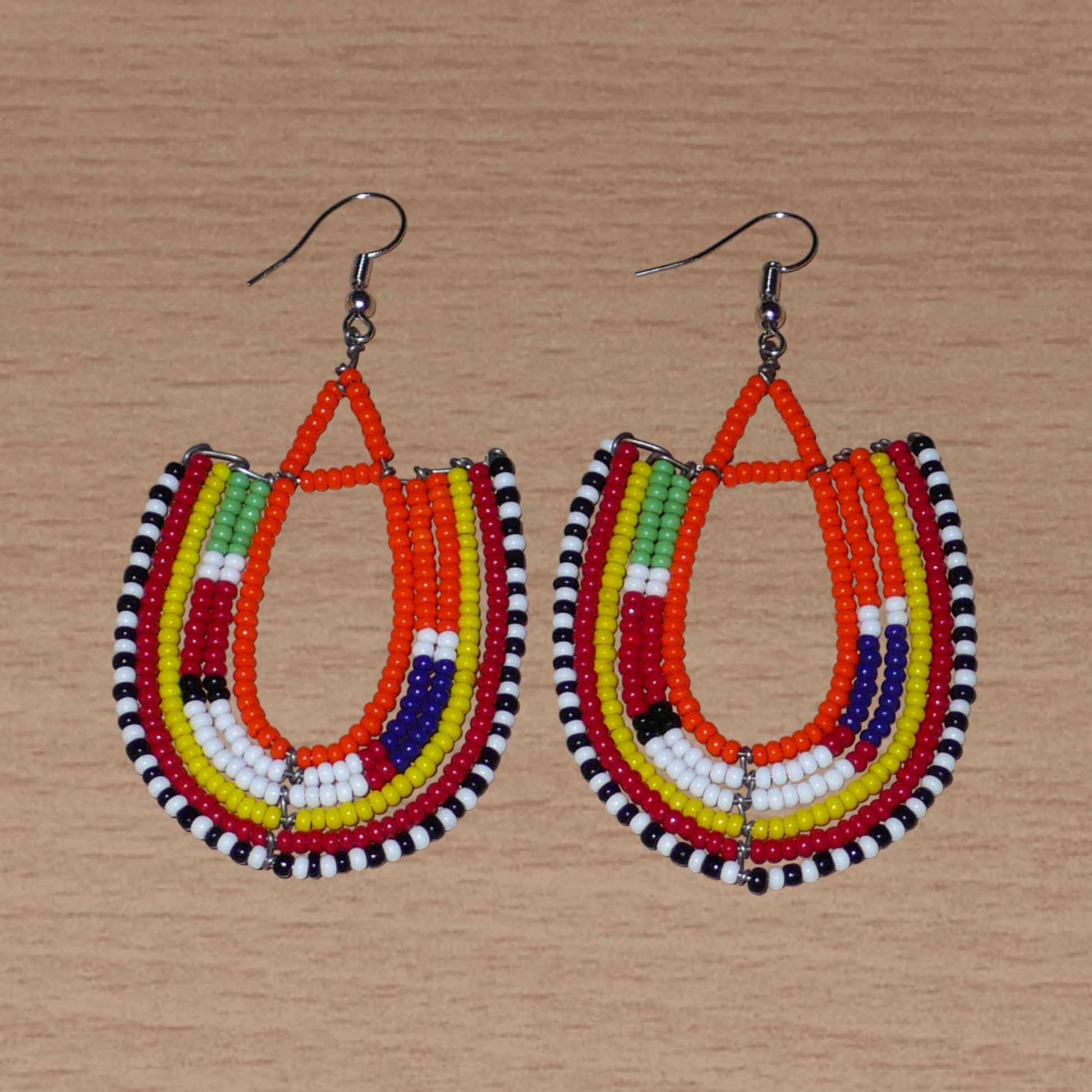 Boucles d'oreilles africaines de tradition ethnique Massai en perles de rocaille orange et multicolores montées en forme d'ancres. Elles mesurent 8 cm de long et se portent sur des oreilles percées.