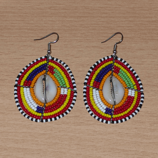 Boucles d'oreilles africaines à motifs ethniques traditionnels Massai composées de perles multicolores et de coquillages cauris ; elles mesurent 7 cm de long et 4 cm de large et se portent avec des crochets en acier inoxydable sur des oreilles percées.