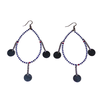 Longues boucles d'oreilles africaines  Massai composées de perles bleu foncé, blanches et rouges enfilées sur un brin de fil de fer monté en forme de goutte, et décorées de chaînettes ornées de disques métalliques. Elles mesurent 11 cm de long et 4,5 cm de large et se portent avec des crochets en acier inoxydable sur des oreilles percées.