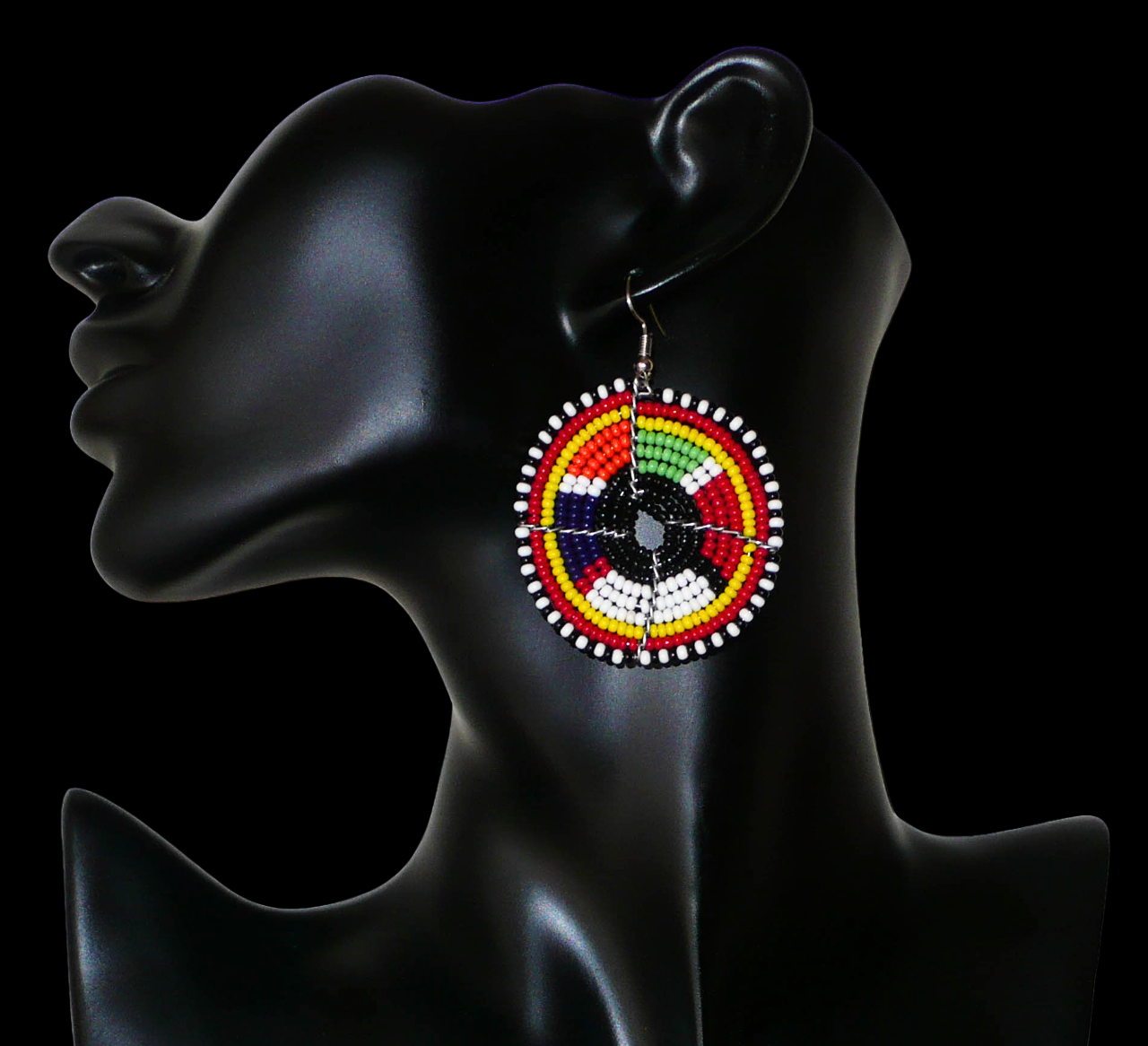 Boucles d'oreilles ethniques à motifs traditionnels Massai noirs et multicolores. De taille moyenne, elles mesurent 6,5 cm de long et 4,5 cm de large et se portent sur des oreilles percées. Photographiées sur un mannequin. Timeless Fineries