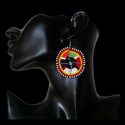 Boucles d'oreilles ethniques rondes à motifs traditionnels Massai en perles noires et multicolores. De taille moyenne, elles mesurent 6,5 cm de long et 4,5 cm de large et se portent sur des oreilles percées.