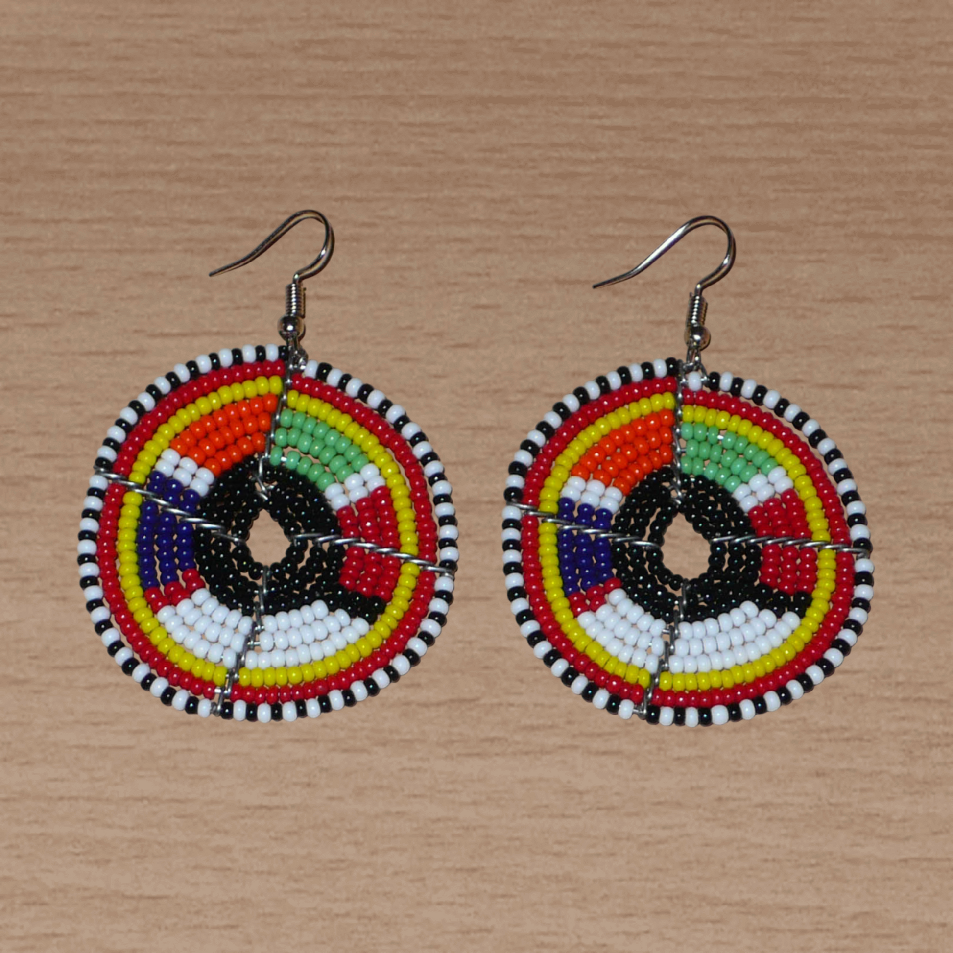 Boucles d'oreilles ethniques rondes à motifs traditionnels Massai en perles noires et multicolores. De taille moyenne, elles mesurent 6,5 cm de long et 4,5 cm de large et se portent sur des oreilles percées.