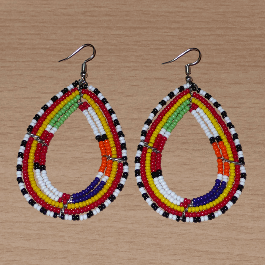 Boucles d'oreilles africaines à motifs ethniques Massai composées de perles de rocaille multicolores glissées sur cinq rangées de fils de fer montés en forme de gouttes. Elles mesurent 8.5 cm de long et 4.5 cm de large, et se portent avec des crochets en acier inoxydable sur des oreilles percées.