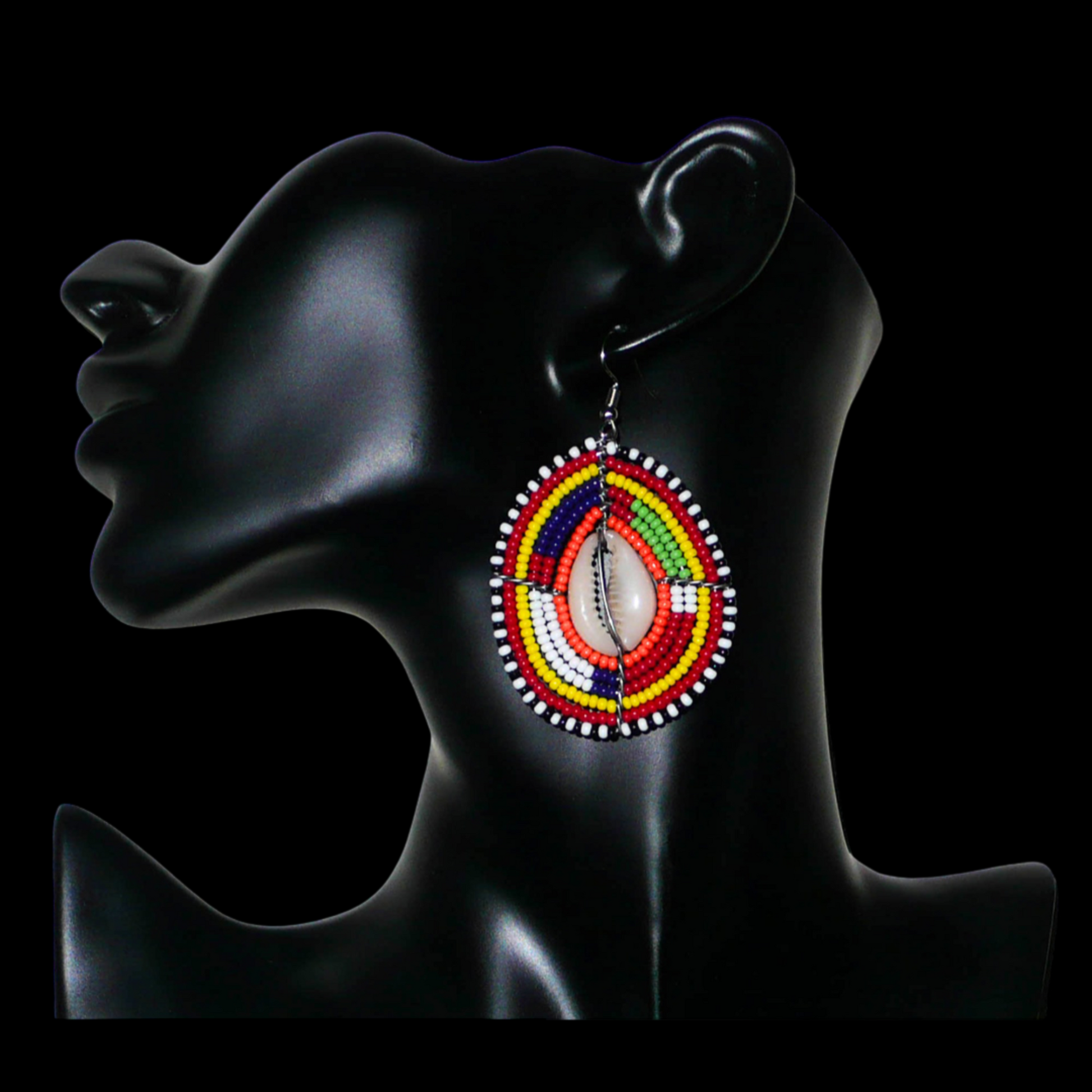 Boucles d'oreilles africaines à motifs ethniques composées de perles et de coquillages montés en forme de boucliers Massai. Elles mesurent 7 cm de long et 4 cm de large et se portent sur des oreilles percées. 