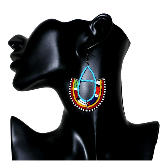 Boucles d'oreilles ethniques Massai bleues et multicolores en perles de rocaille montées en forme d'ancres. Elles mesurent 7.5 cm de long et se portent sur des oreilles percées.