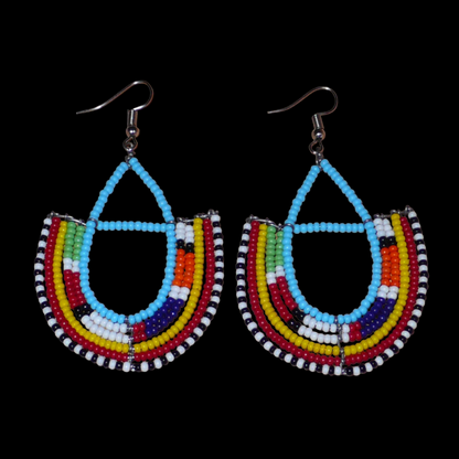 Boucles d'oreilles ethniques Massai bleues et multicolores en perles de rocaille montées en forme d'ancres. Elles mesurent 7.5 cm de long et se portent sur des oreilles percées.