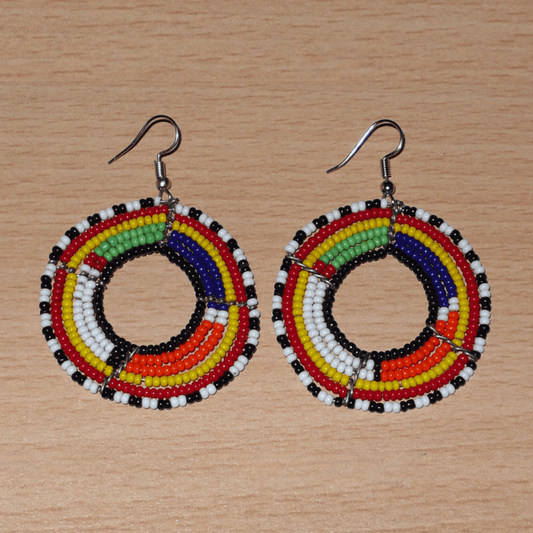 Boucles d'oreilles africaines perlées se composant de perles de rocaille enfilées sur des structures circulaires faites de six rangées de fils de fer. Elles mesurent 7 cm de long et 5 cm de large et se portent avec des crochets en acier inoxydable.