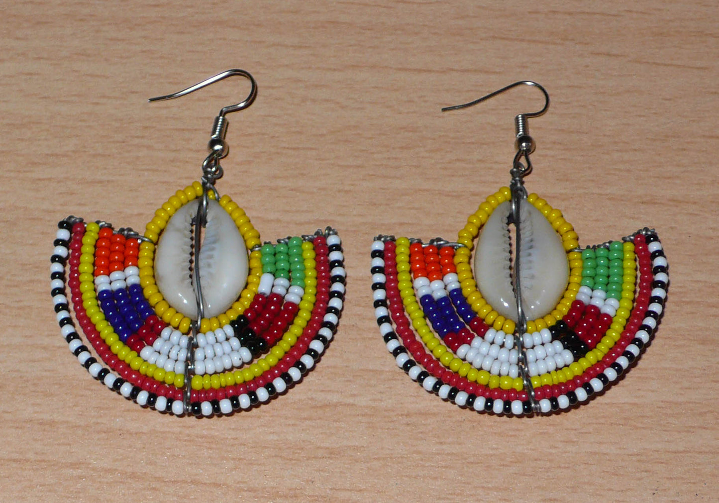 Ces jolies boucles d'oreilles à l'allure ethnique afro chic se composent de perles de rocaille jaunes et multicolores et de coquillages cauris. De taille moyenne, elles mesurent 6 cm de long et 4.5 cm de large, et se portent avec des crochets en acier inoxydable sur des oreilles percées.