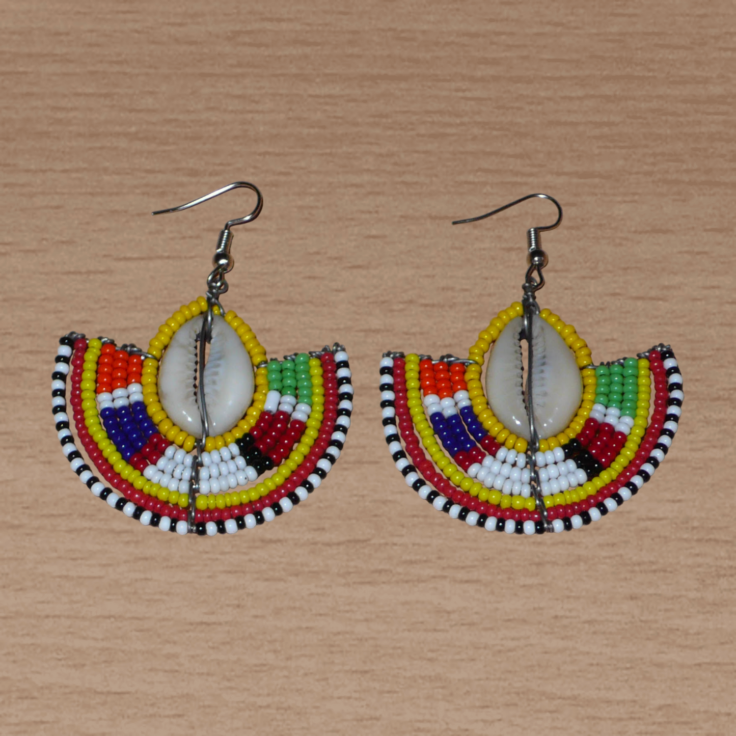 Ces jolies boucles d'oreilles à l'allure ethnique afro chic se composent de perles de rocaille jaunes et multicolores et de coquillages cauris. De taille moyenne, elles mesurent 6 cm de long et 4.5 cm de large, et se portent avec des crochets en acier inoxydable sur des oreilles percées.