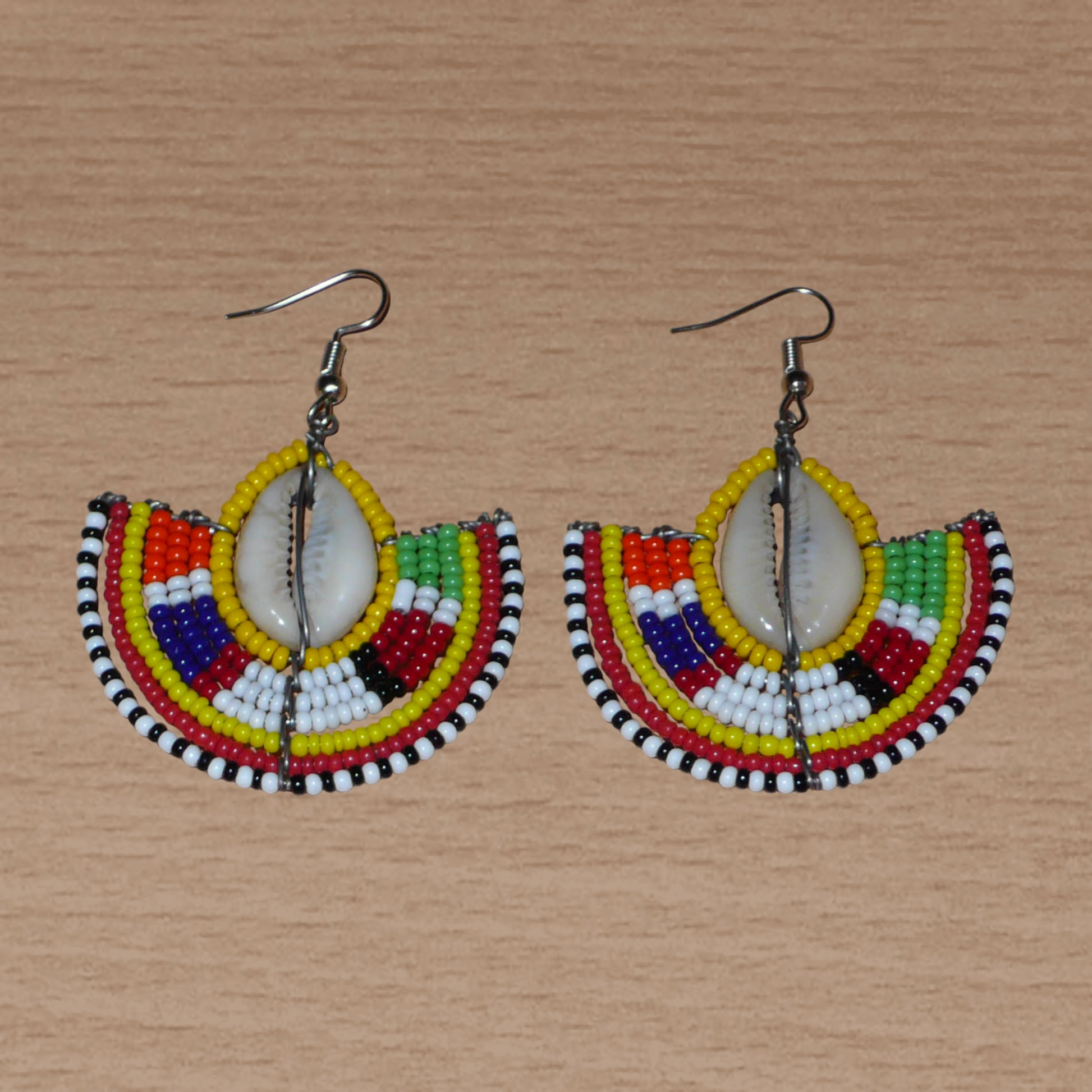 Ces jolies boucles d'oreilles à l'allure ethnique afro chic se composent de perles de rocaille jaunes et multicolores et de coquillages cauris. De taille moyenne, elles mesurent 6 cm de long et 4.5 cm de large, et se portent avec des crochets en acier inoxydable sur des oreilles percées.