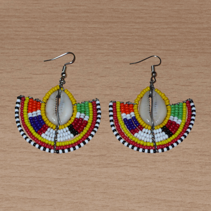 Ces jolies boucles d'oreilles à l'allure ethnique afro chic se composent de perles de rocaille jaunes et multicolores et de coquillages cauris. De taille moyenne, elles mesurent 6 cm de long et 4.5 cm de large, et se portent avec des crochets en acier inoxydable sur des oreilles percées.