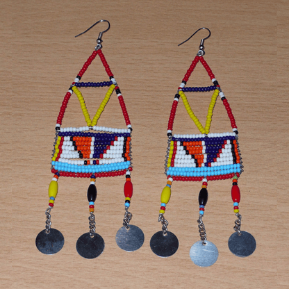 Boucles d'oreilles africaines de tradition Massai composées de perles de rocaille et de perles en plastique rouges et multicolores glissées sur des structures géométriques rigides en fils de fer ; elles se prolongent de chaînettes décorées de disques métalliques. Surdimensionnées, ces longues boucles d'oreilles de style résolument ethnique mesurent 13 cm de long et 4 cm de large ; elles se portent avec des crochets en acier inoxydable sur des oreilles percées.